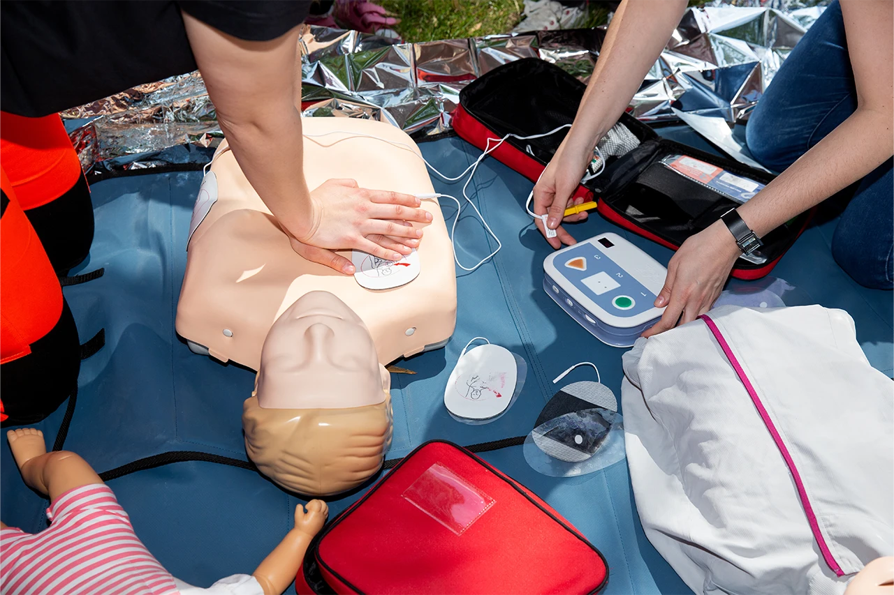 Person providing CPR to a dummy with a defibrillator
