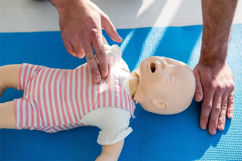 A person providing CPR to an infant dummy