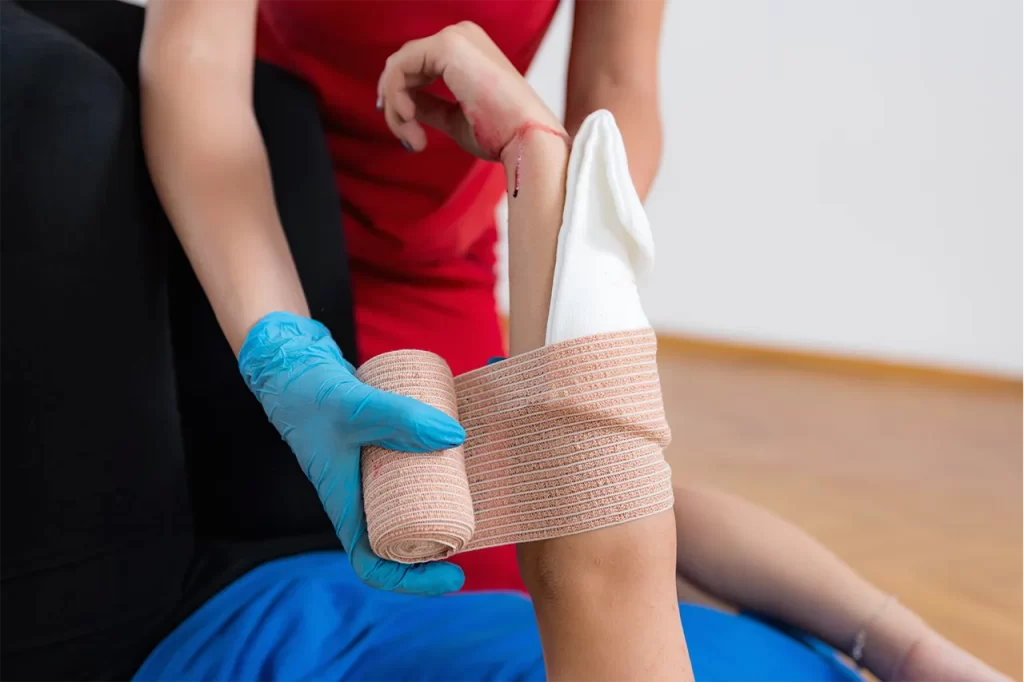 A person applying a bandage to another person's arm