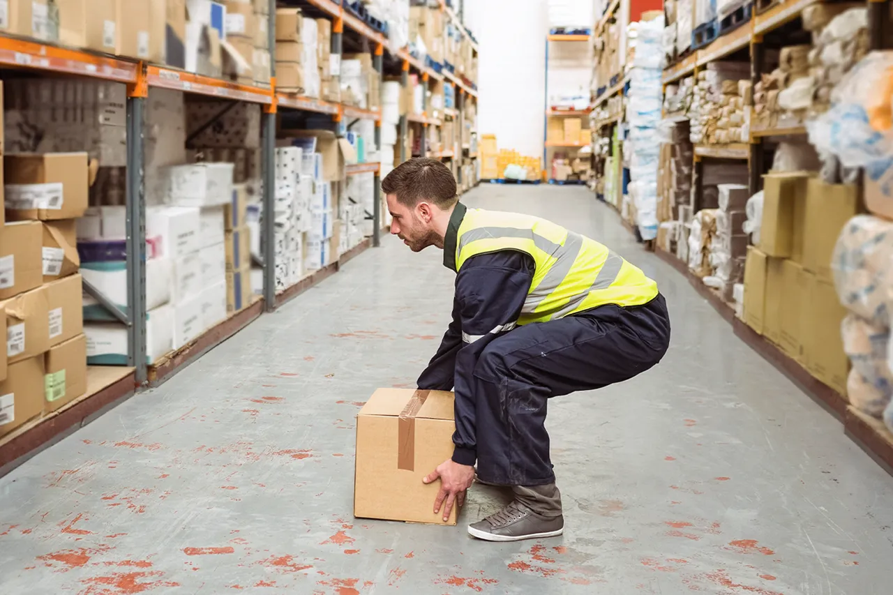 A man in a hi vis vest safely lifting a box
