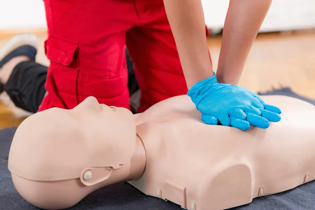 A person applying CPR compressions to a dummy